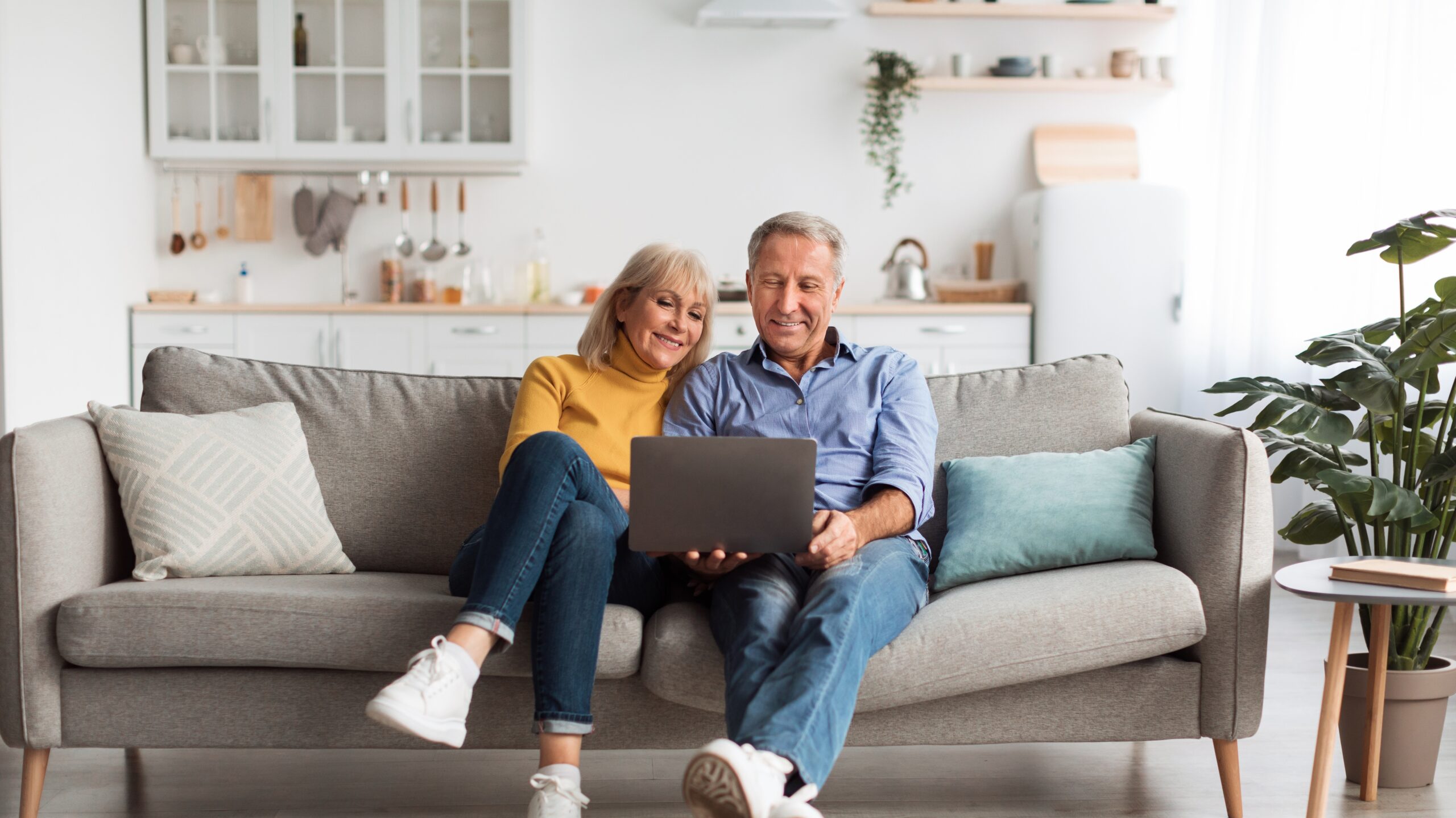 Senior,Spouses,Using,Laptop,Watching,Movie,Together,Sitting,On,Couch